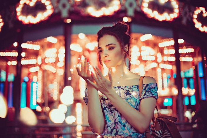 Woman holding fairy lights with carousel lights in background