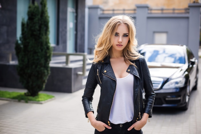 Woman in leather jacket with car