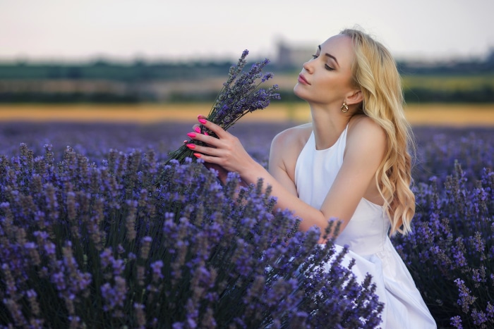 Woman in white dress holding lavender in a field