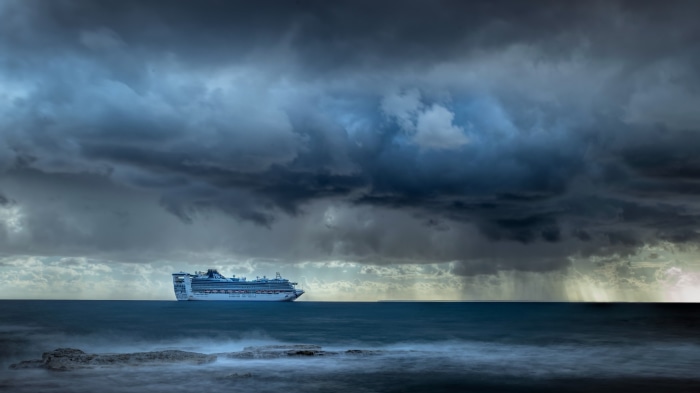 Cruise ship sailing under stormy clouds