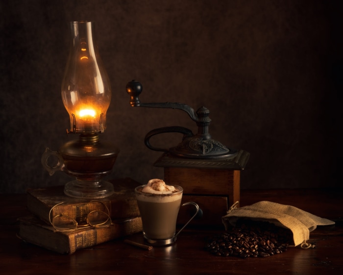 Still life with oil lamp, coffee, and books