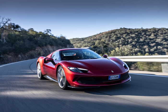 Red Ferrari 296 GTB driving on a winding road