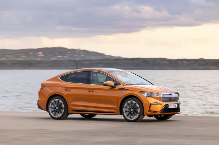 Orange Škoda Enyaq iV 80 electric car driving by water
