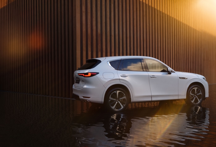 White Mazda CX-60 SUV parked near a wooden wall