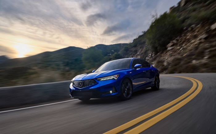 Blue Acura Integra driving on a mountain road