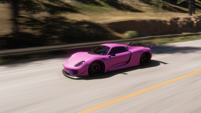 Pink Porsche 918 Spyder driving on a road