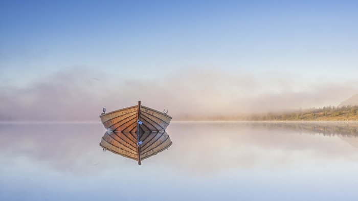Wooden boat on a misty lake with reflection