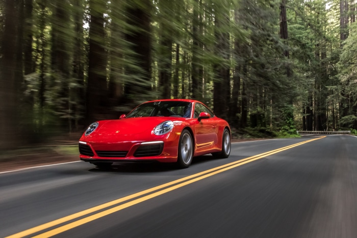 Red Porsche 911 Carrera driving on a forest road