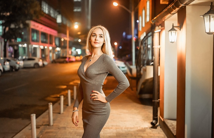 Woman in a grey dress on a city street at night