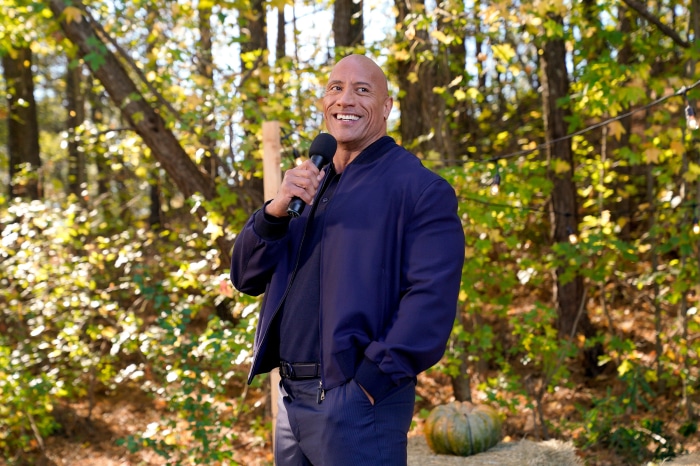 Dwayne Johnson holding a microphone outdoors