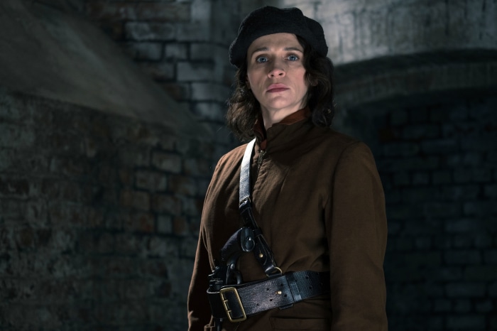 Woman in brown coat and beret with gun holster