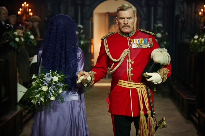 Man in military uniform and veiled woman with bouquet