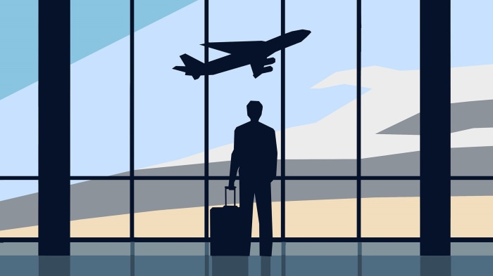 Silhouette of a man with luggage at airport watching plane take off