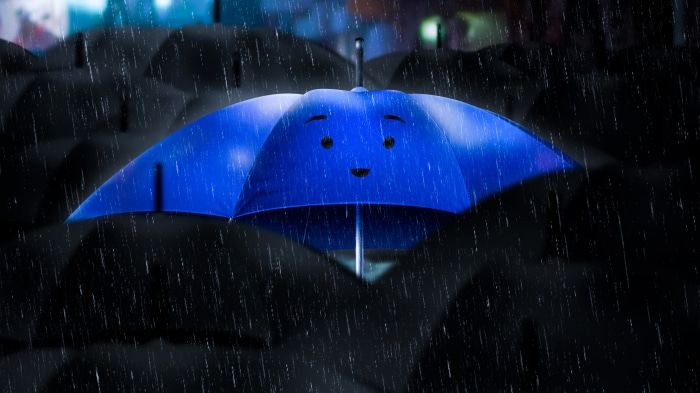 A blue umbrella with a face in the rain