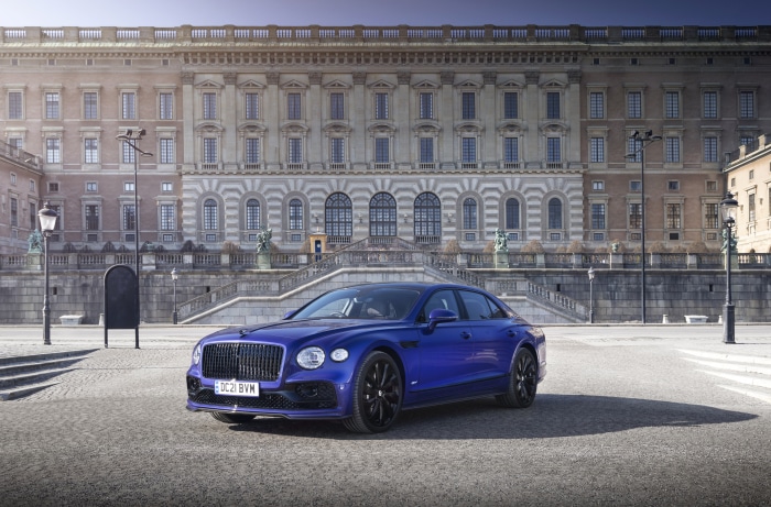 Blue Bentley Flying Spur parked in front of a palace