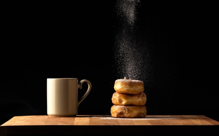 Stack of donuts with powdered sugar and coffee mug