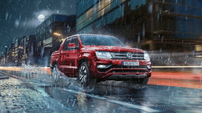 Red Volkswagen Amarok driving through rain at night