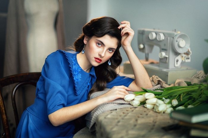 Woman in blue dress with sewing machine and tulips