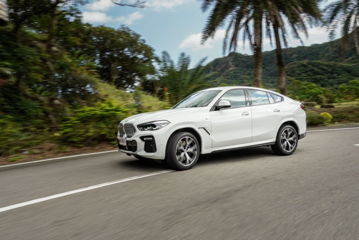 White BMW X6 driving on a road