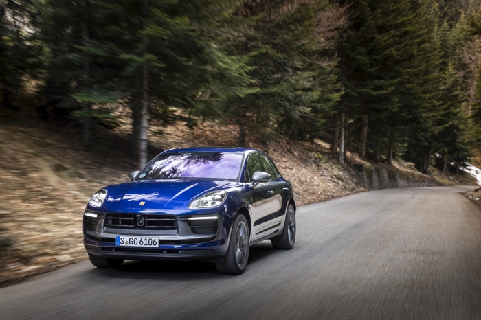 Blue Porsche Macan Turbo driving on a forest road