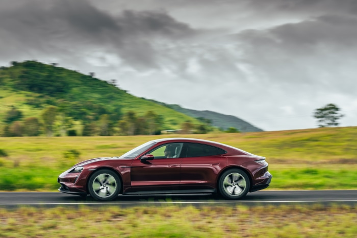 Red Porsche Taycan driving on a road