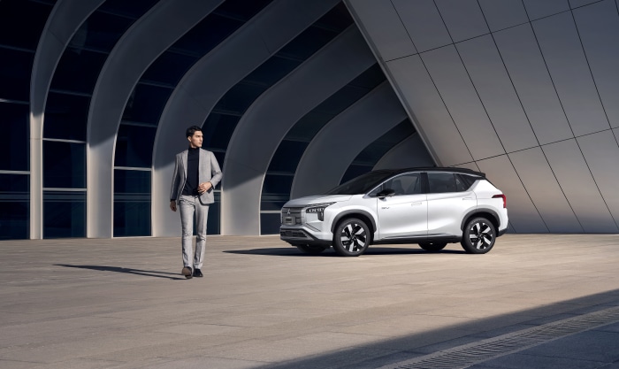 Mitsubishi Airtrek EV parked next to a man in a suit