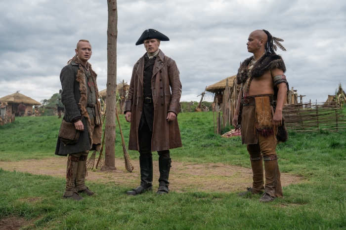 Jamie Fraser and two men in a village