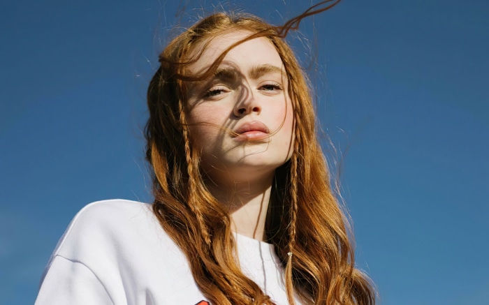Sadie Sink with red hair against blue sky