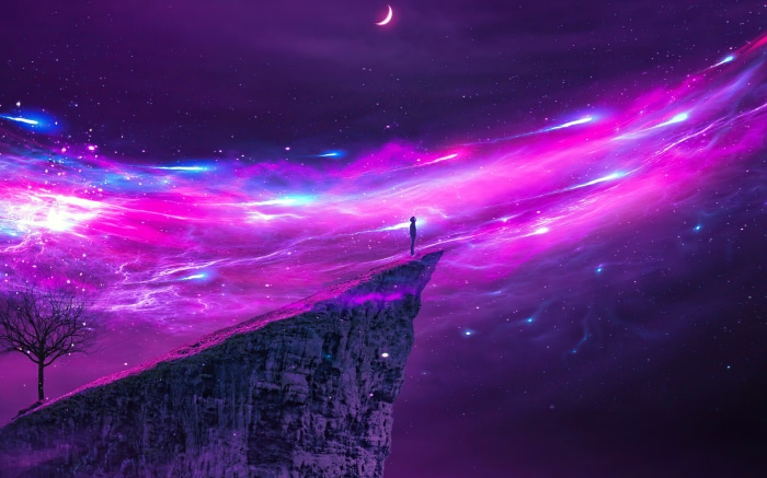 Person standing on cliff edge under nebula