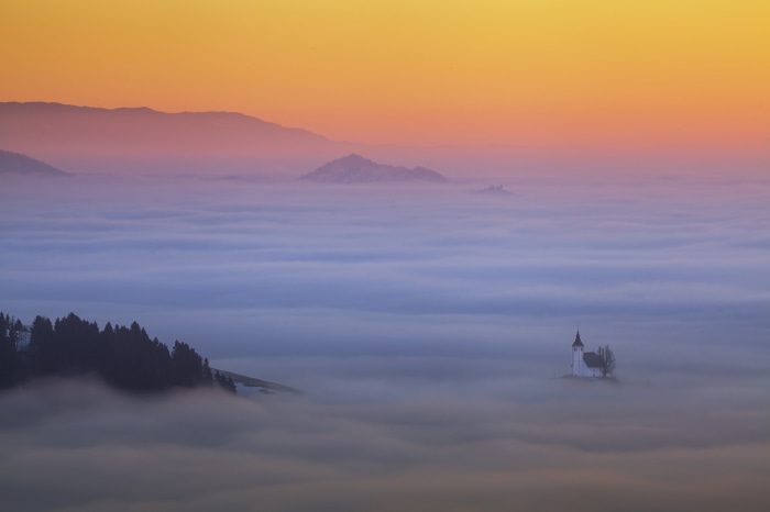 Church above a sea of clouds at sunrise