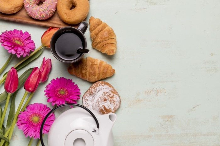 Still life with donuts, croissants, coffee, and flowers