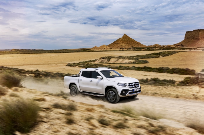 White Mercedes-Benz X-Class driving on dirt road in desert