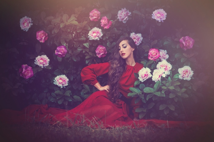 Woman in red dress among pink and white roses