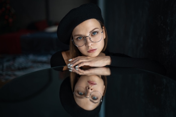 Woman wearing glasses and beret with reflection