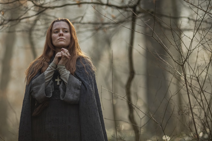 Woman in medieval dress praying in forest