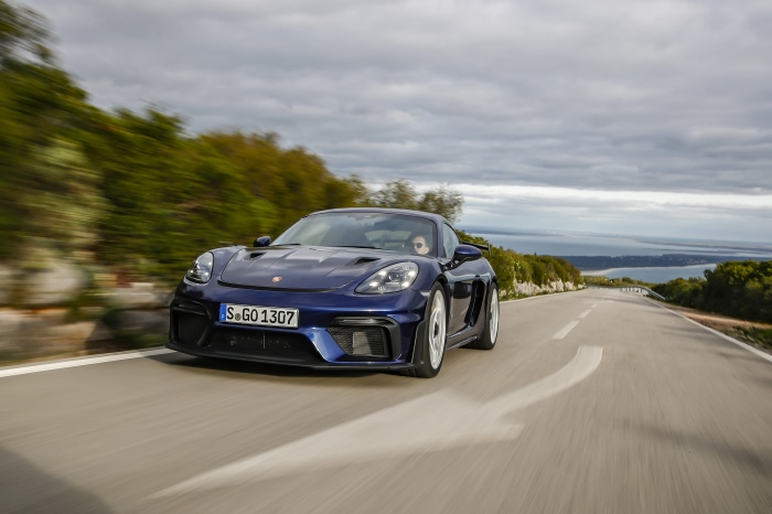 Porsche 718 Cayman GT4 driving on a coastal road