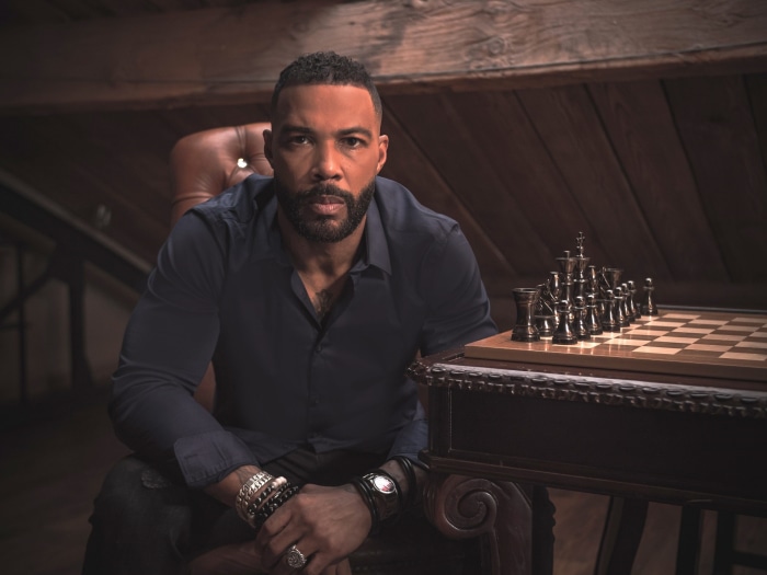 Omari Hardwick sitting by a chessboard