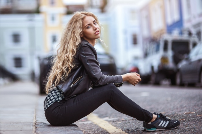 Woman in leather jacket sitting on street