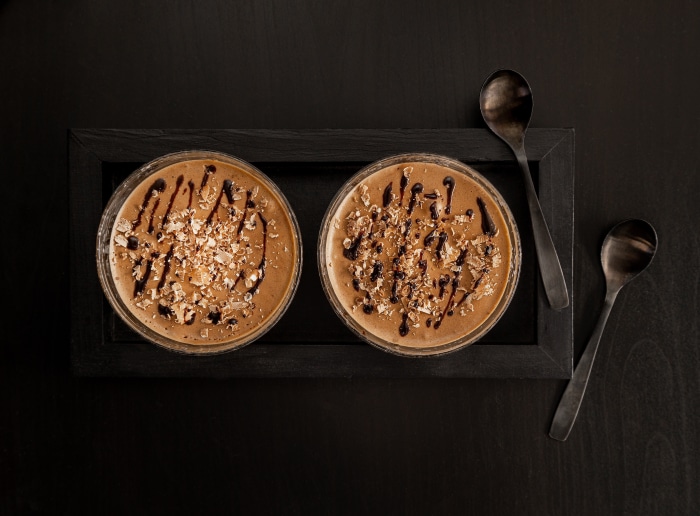 Two coffee mousses with chocolate drizzle and nuts