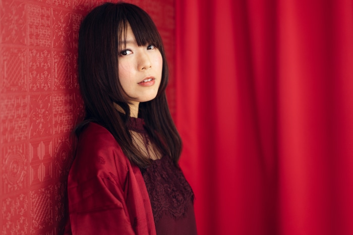 Asian woman in red attire against red textured wall