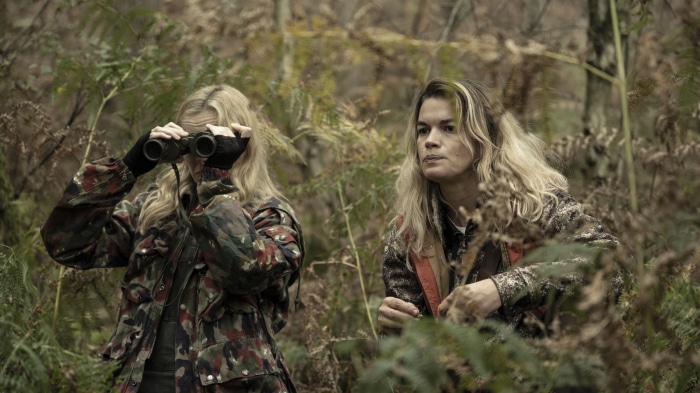 Two women with binoculars in a forest