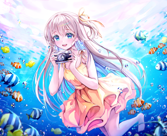 Girl with camera underwater with fish