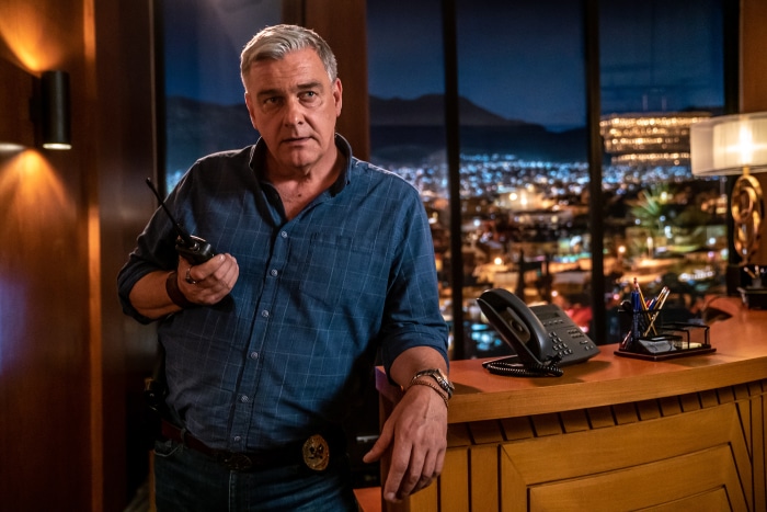 Ray Stevenson in an office with a city view
