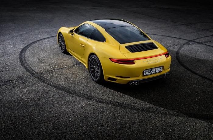 Yellow Porsche 911 Carrera 4S on asphalt with tire marks