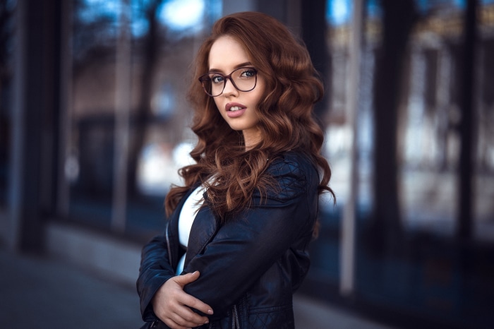 Redhead woman with glasses wearing a leather jacket