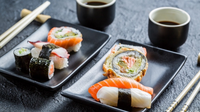 Sushi and soy sauce on black plates with chopsticks