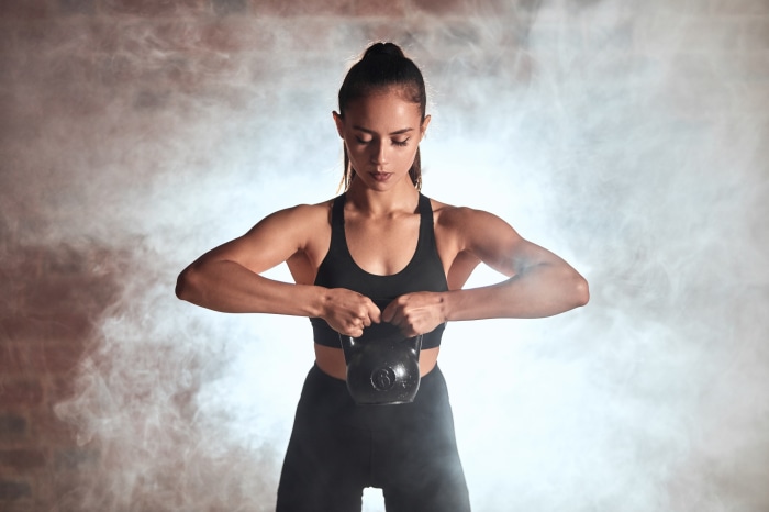 Woman performing kettlebell exercise with smoke background