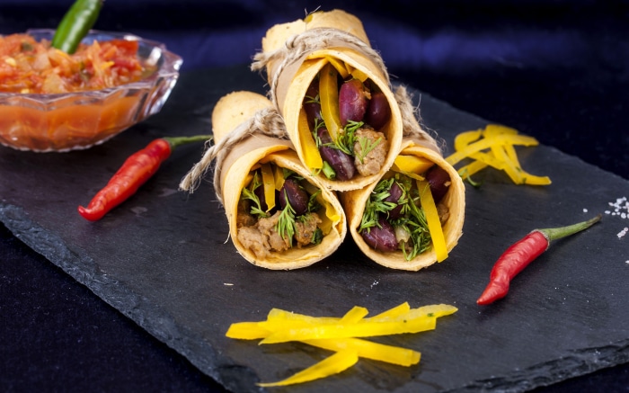 Three burritos with salsa and chili peppers