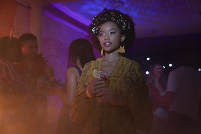 Young woman with flowers in her hair holding a drink at a party