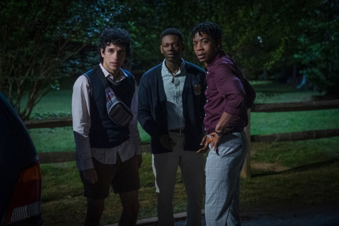 Three young men standing outdoors at night